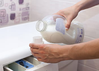 Someone adding laundry detergent to the washing machine