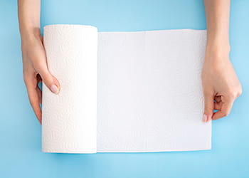 Hands holding paper towel on a blue background