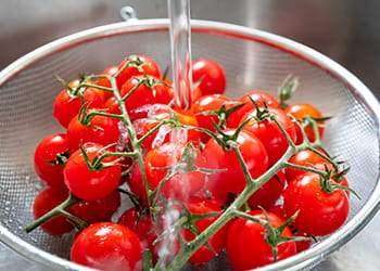 Cherry tomatoes being washed in a sieve