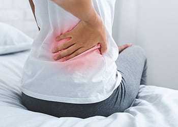 person with back pain holding lower back