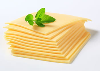stack of sliced cheese with basil leaves on top