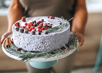 woman holding cake decorated with berries