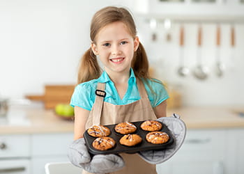 Young girl holding a tray of homemade muffins