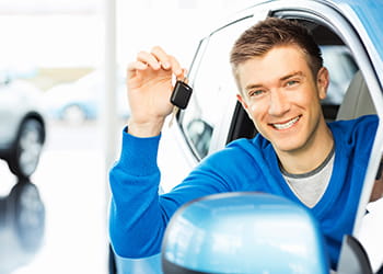 Happy driver in a blue car holding car key