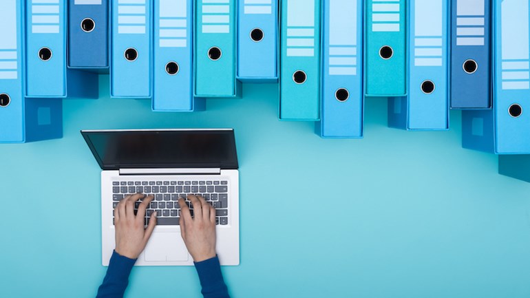 Graphic showing a persons arms typing on a laptop with document binders lined in a row above.