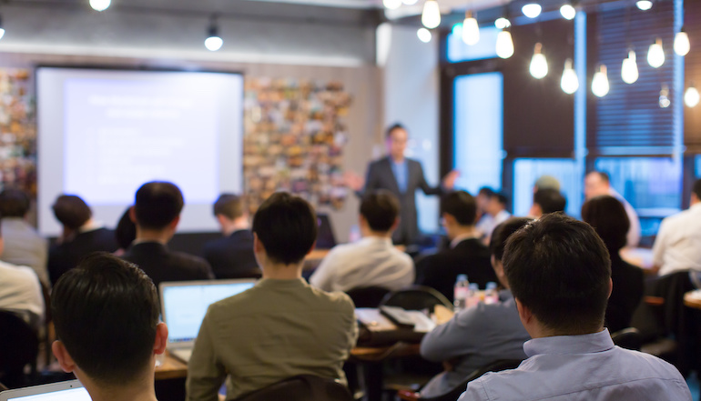 A group of business individuals attend a conference in a conference room. 