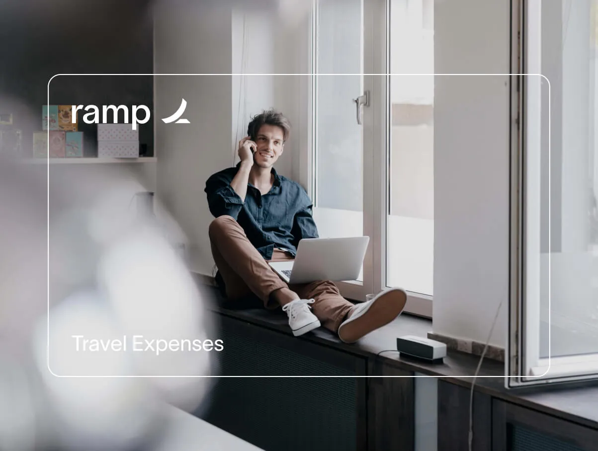 The silhouette of a Ramp card for 'Travel Expenses' frames a man working on his laptop, sitting on a window ledge of a café.