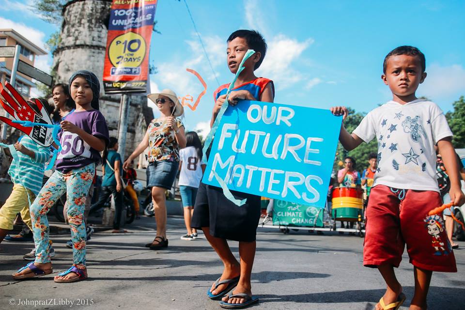 Several children walking in a march and one holding a blue poster saying "Our Future Matters"
