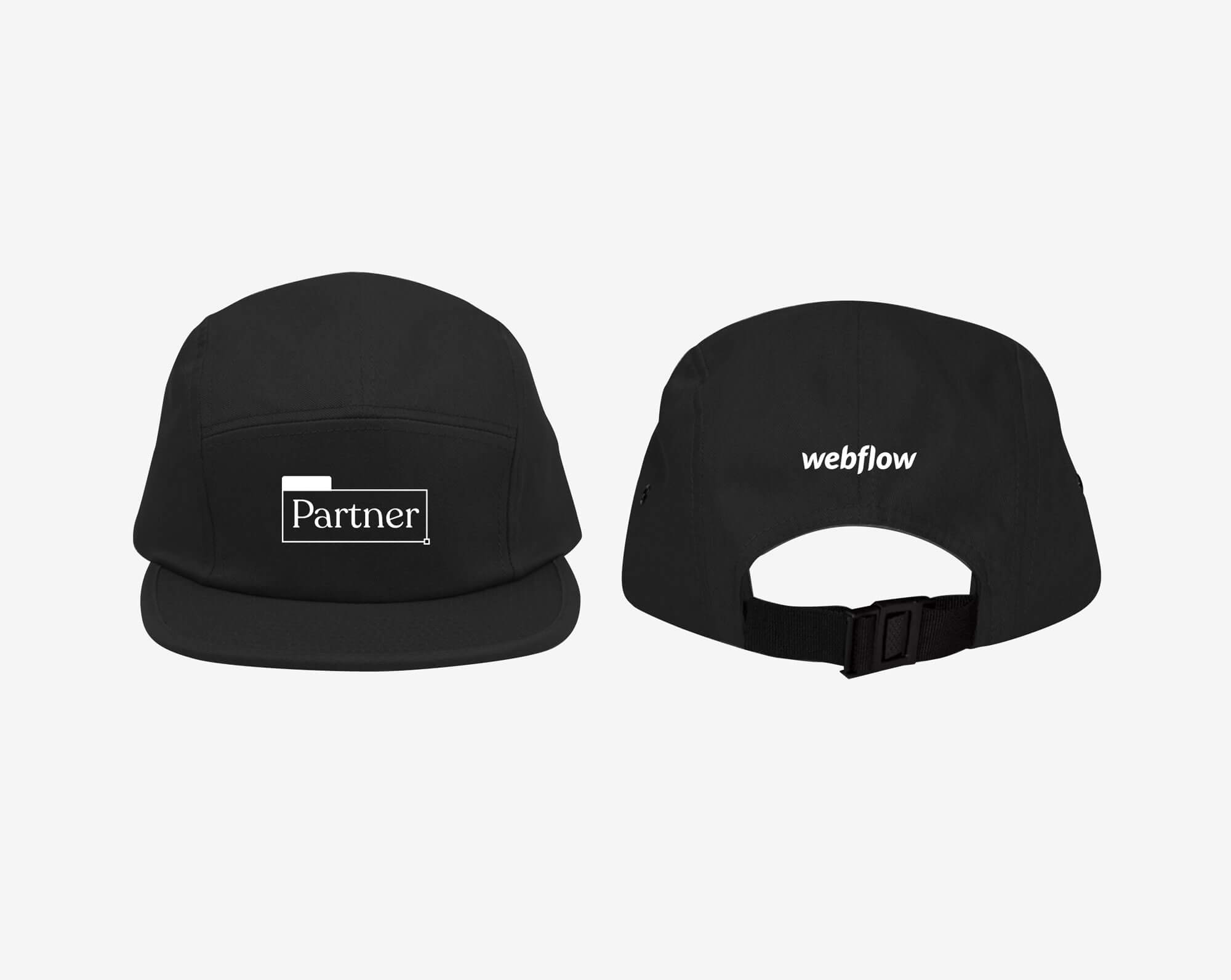 A black camper-style cap with a low profile, nylon strap clip closure, and a white embroidered design on the front saying "Webflow Partner" along with a white Webflow logo on the back.