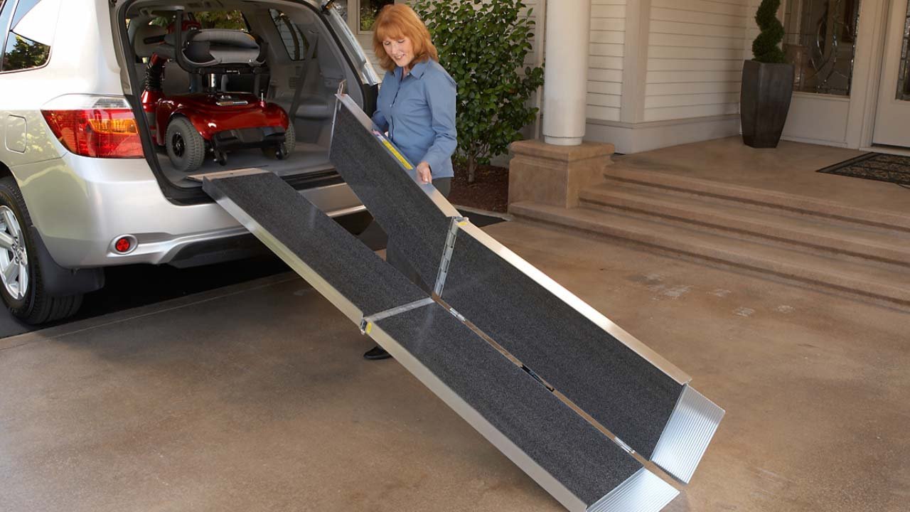 Woman folding the EZ Access Trifold Ramp outside of a SUV's tailgate.