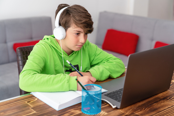 A middle school boy remote learning with his laptop and headphones.