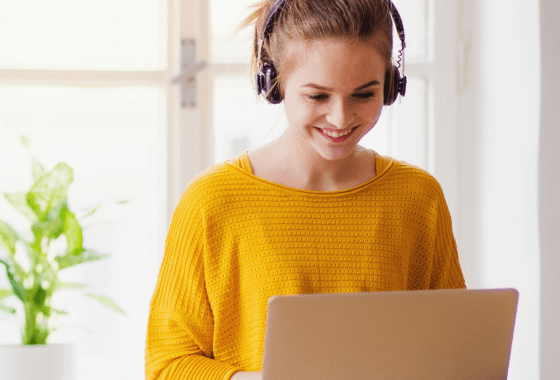 A high school girl attending class remotely with her laptop and headphones.
