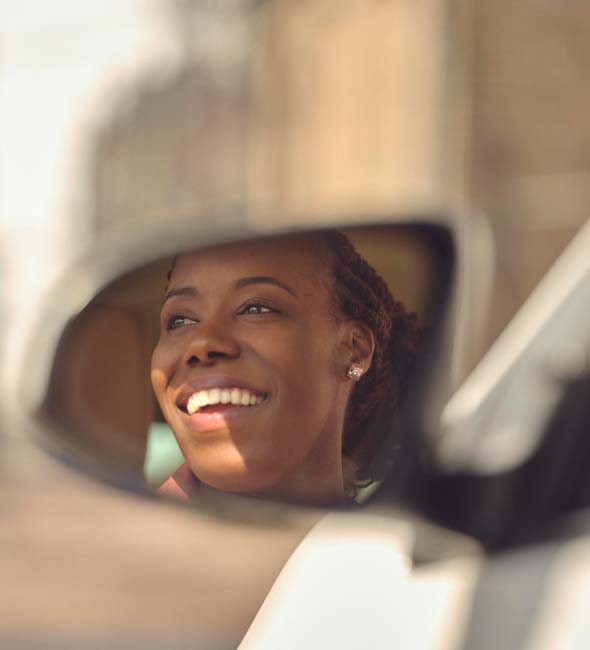 Woman smiling seen on the side mirror