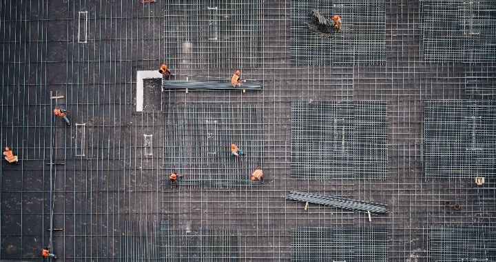 Aerial view of construction workers building a skeleton frame with steel columns.
