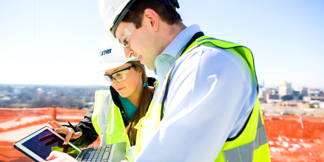 Two Turner Construction workers viewing a digital workforce management platform on site.