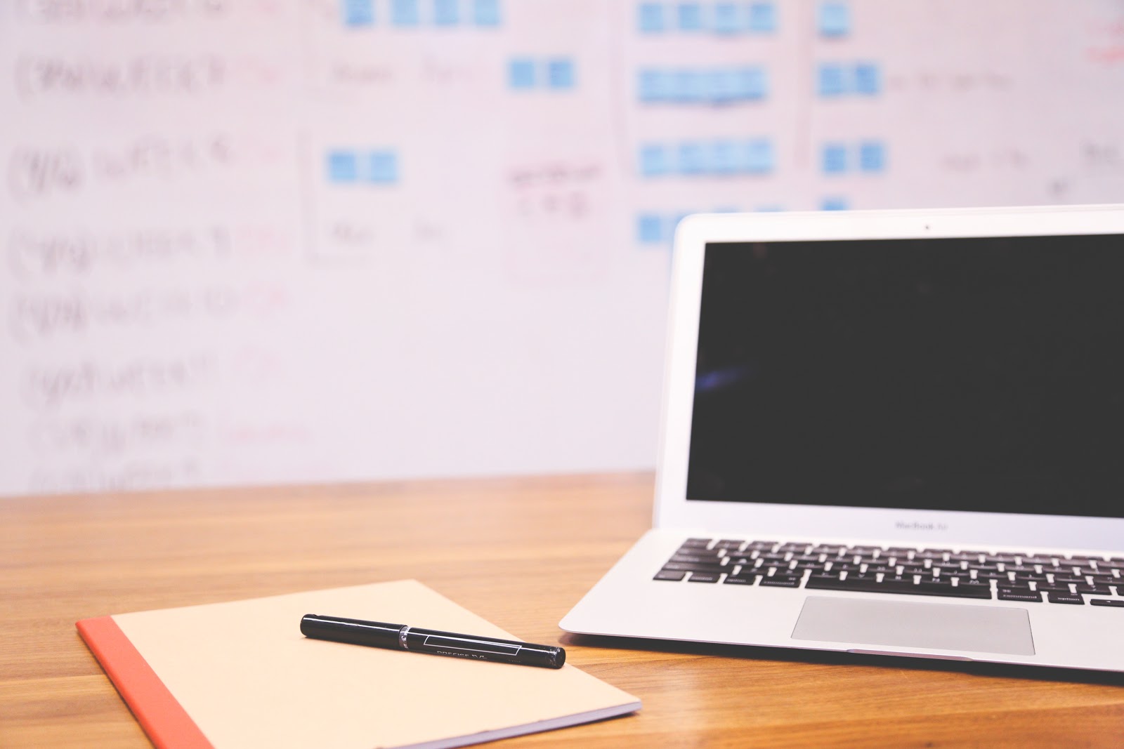 A notebook and pen sitting next to a computer