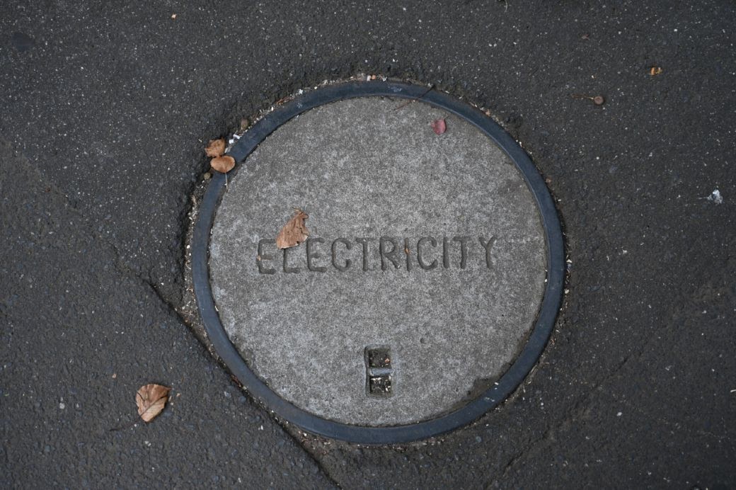 A manhole cover with the word, “electricity,” in the middle.
