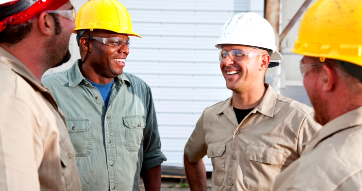 Four construction workers talking and laughing in a circle.