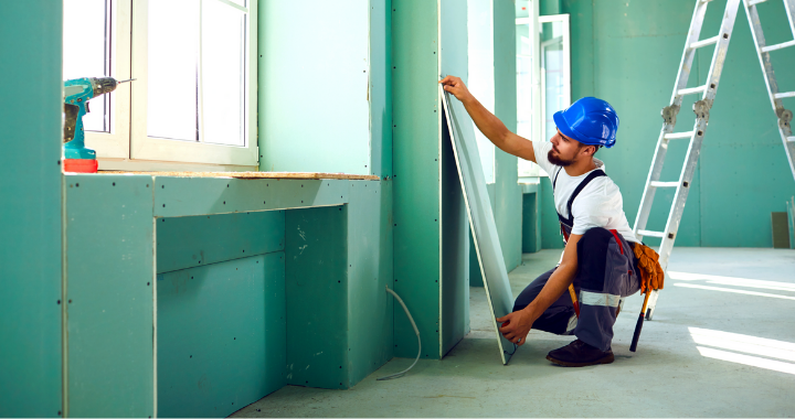 A construction worker constructing walls and ceilings structures in a building.