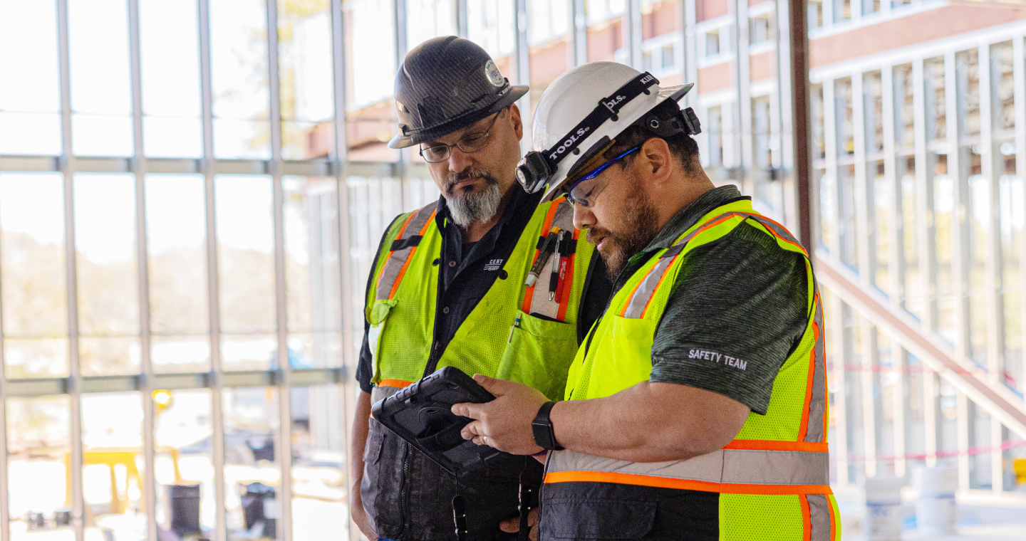 On a jobsite, two labor managers track certifications on a tablet.