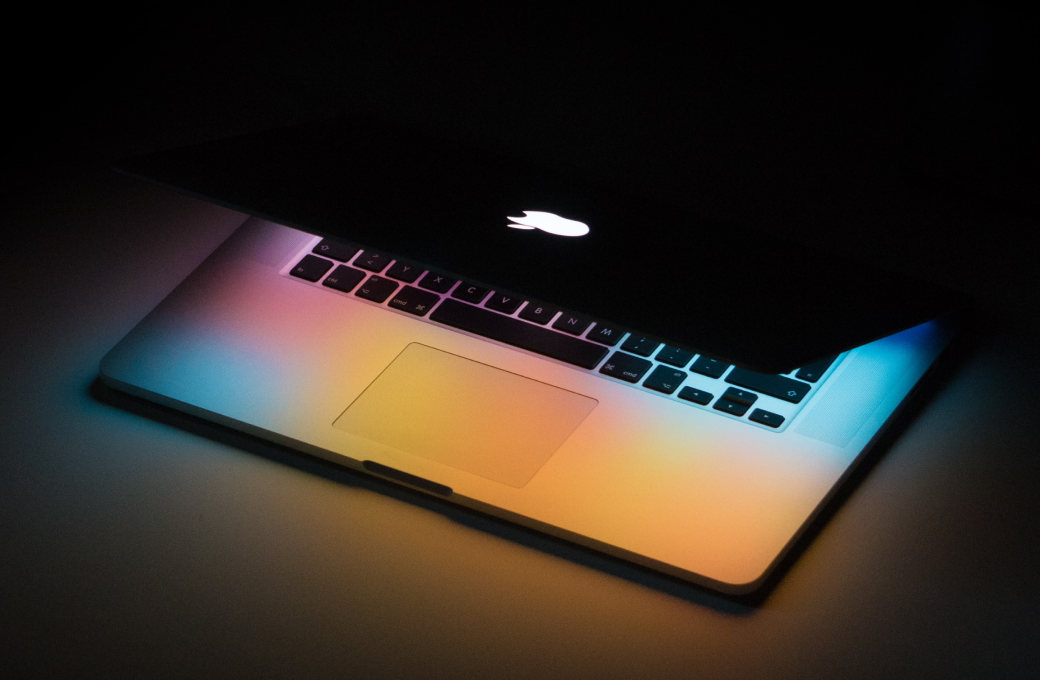 Mac laptop partially open displaying rainbow light