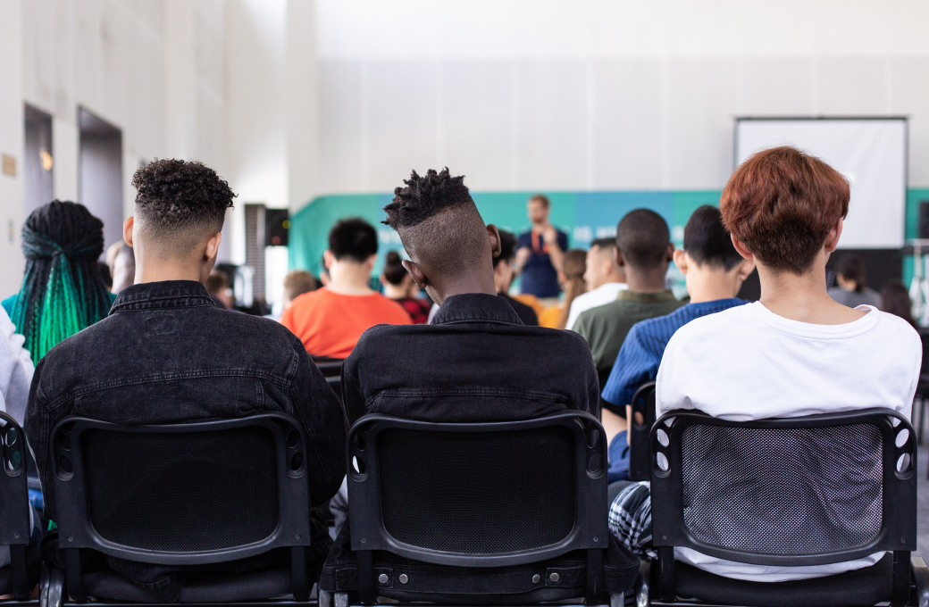 Three students sitting in chairs listening to a class lecture