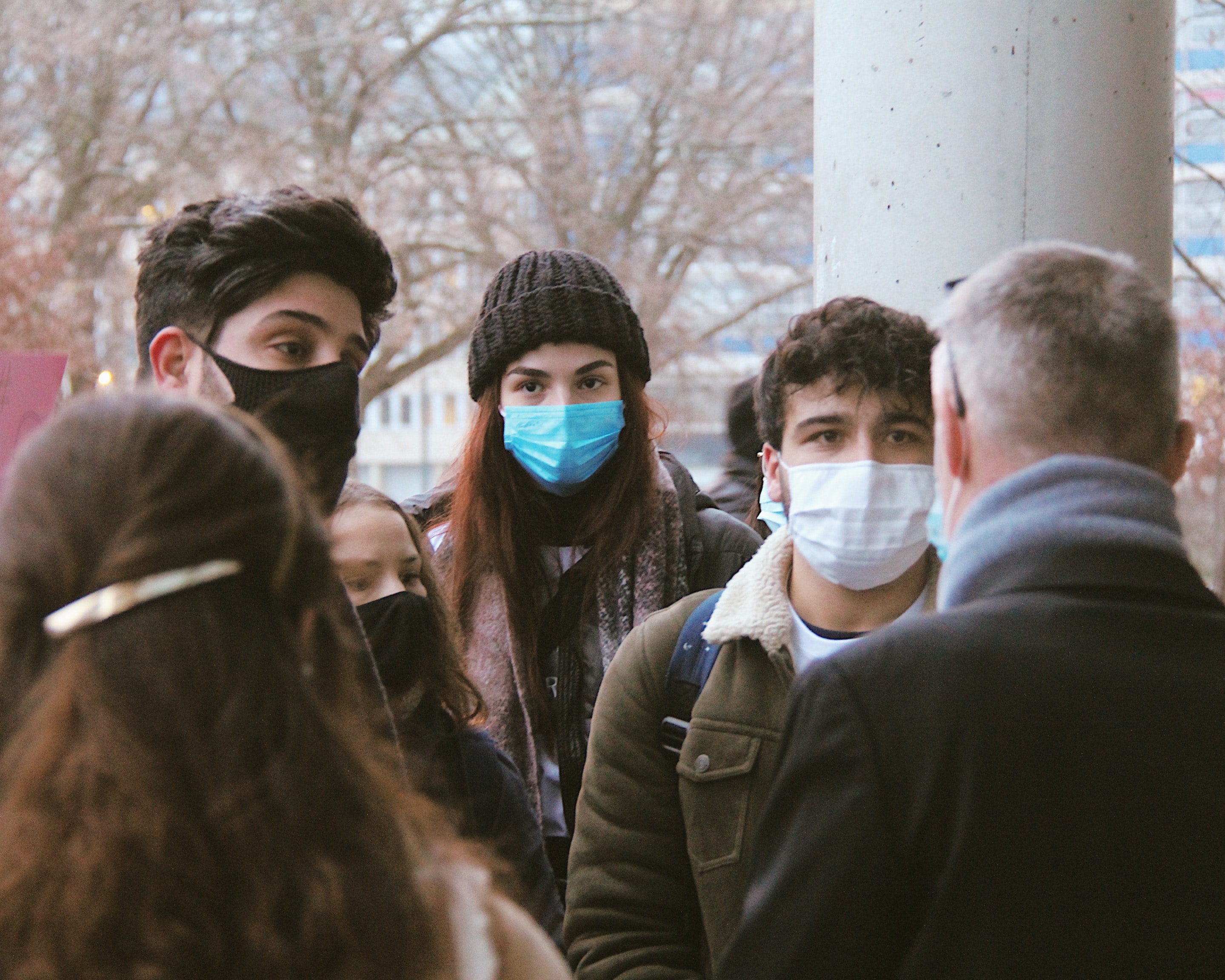 Students standing outside in winter coats and medical face masks