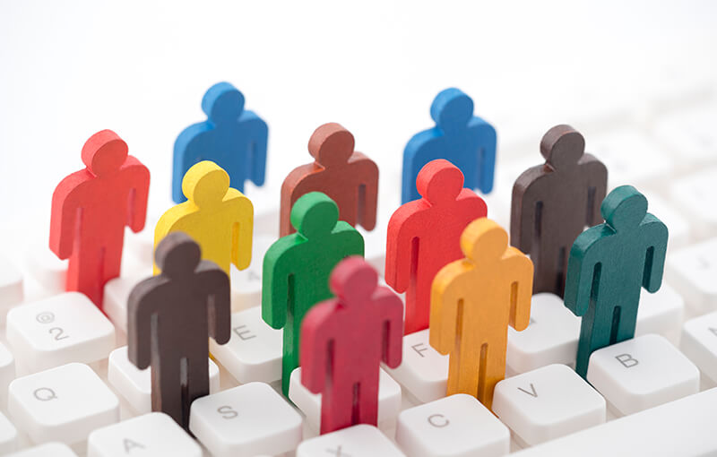 Colorful wooden figures representing people standing on a keyboard, sandwiched between the keys.