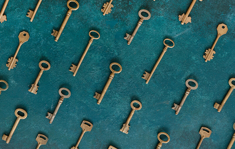 Pattern of antique gold keys laying diagonally in lines against a background painted dark teal.