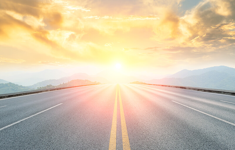 A straight road continuing off into the horizon at dawn.