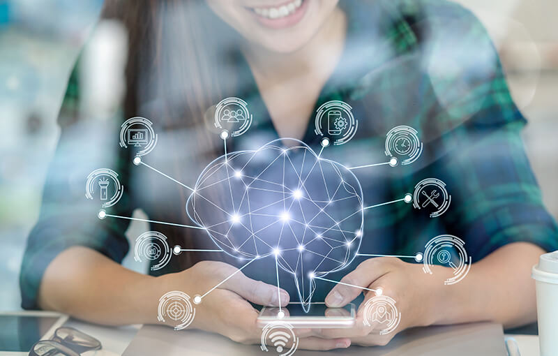 Someone holding a smartphone with a wire-frame brain overlaid and several lines coming off and pointing to various icons representing choices - Neovation Learning Solutions