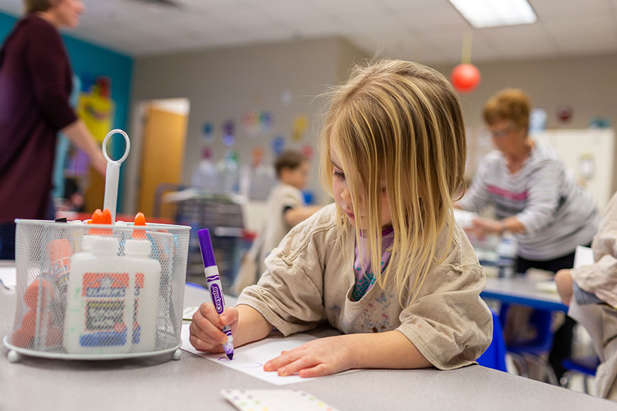 preschool girl coloring with markers