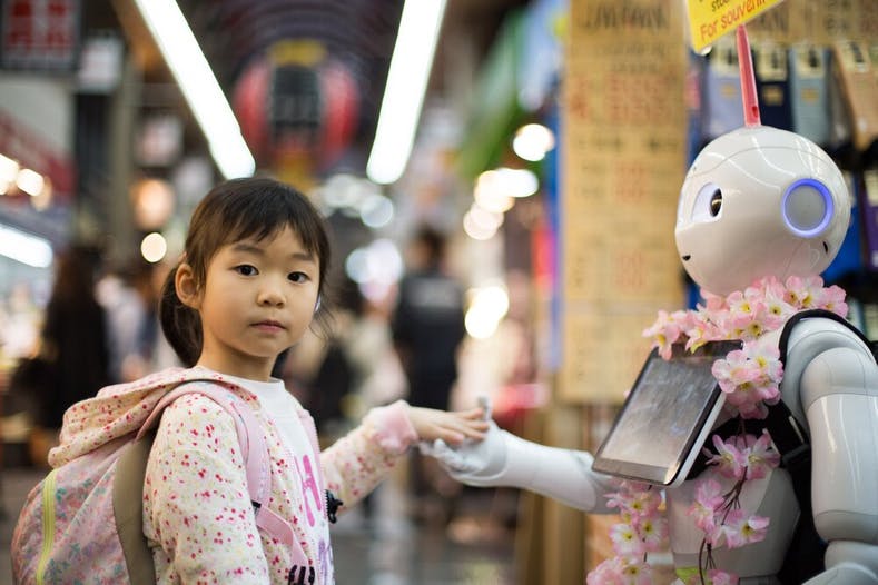 Image of little girl holding hands with a small robot