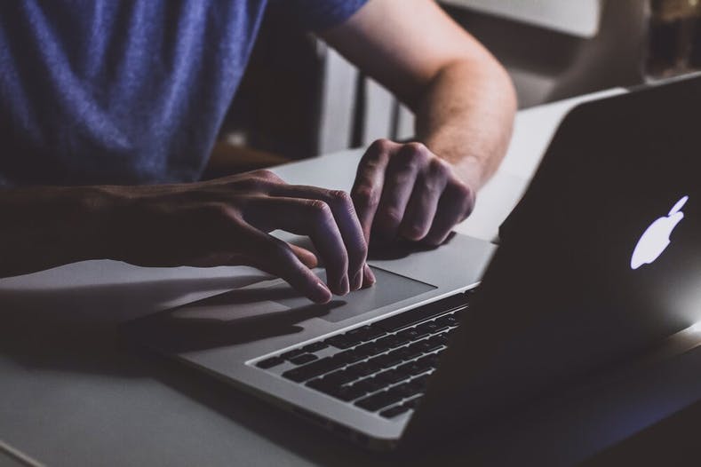 Image of man typing on laptop.