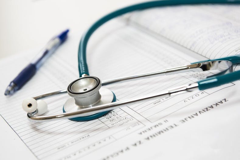 Image of a doctor's stethoscope against blank insurance claims forms.
