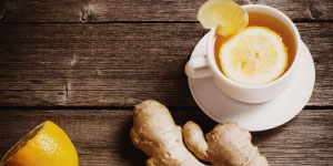 Cup of ginger tea on a table surrounded by raw ginger roots