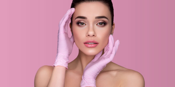 Woman with surgical gloves on holding her face