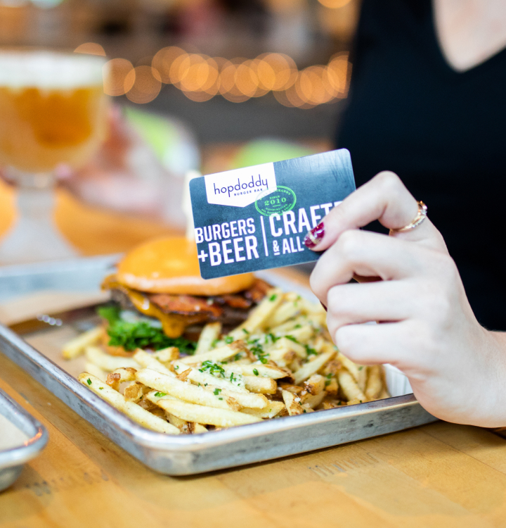 Hopdoddy gift card held above fries and burger.