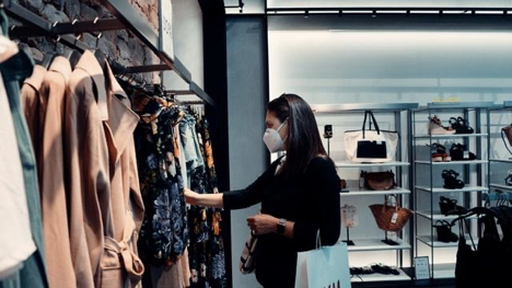 woman shopping at clothing store with mask on