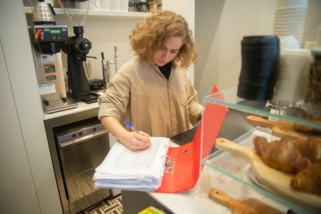 woman manually managing inventory at cafe