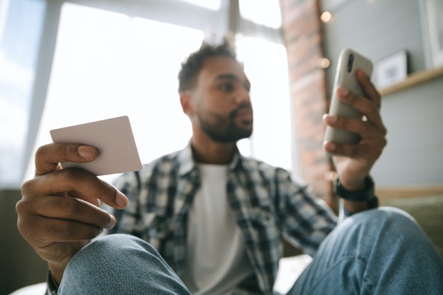 man holding smartphone and credit card