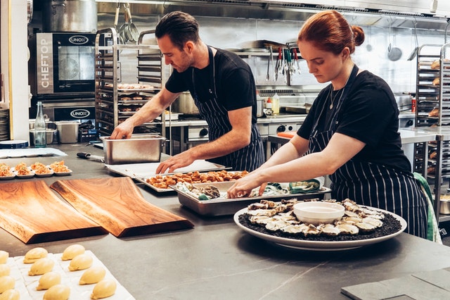 two chefs preparing food in kitchen