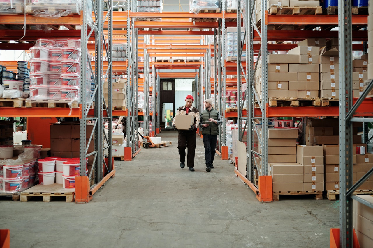 Two men walking between shelves in a warehouse