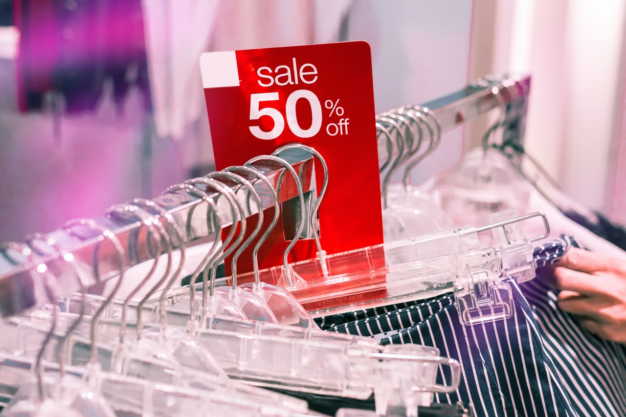 A clothes rack with a “50% Off” Sale sign