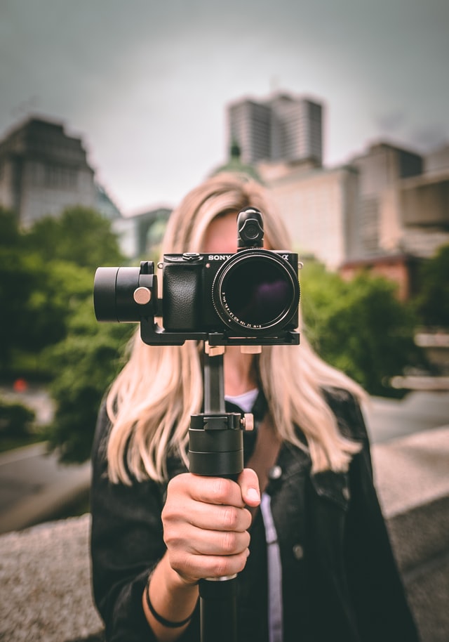 Woman holding camera by handheld tripod