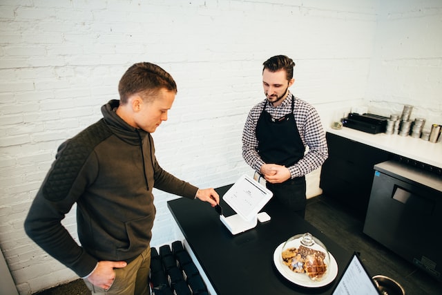 A small business owner watching a customer pay on a POS system