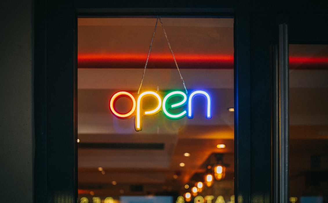 A rainbow colored open sign on window