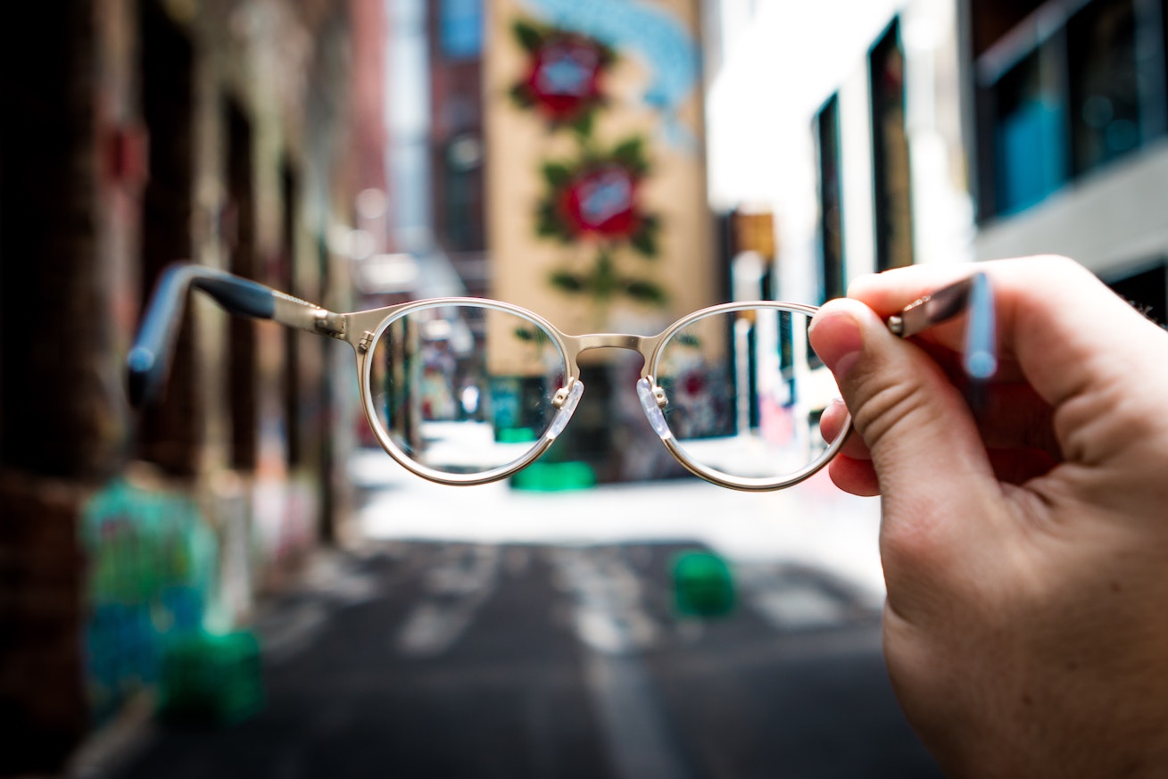 A glasses in front of a photo of a busy city street
