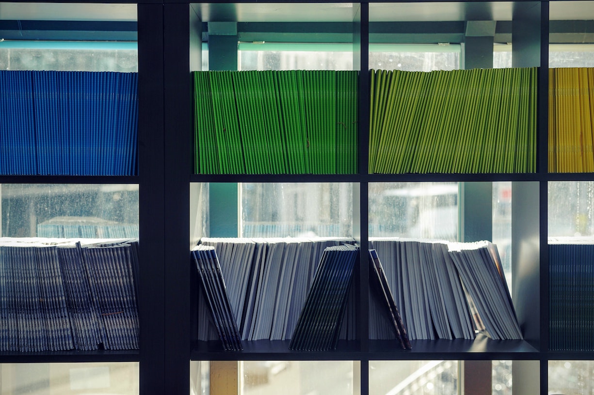 A well organized bookshelf showing color coded books