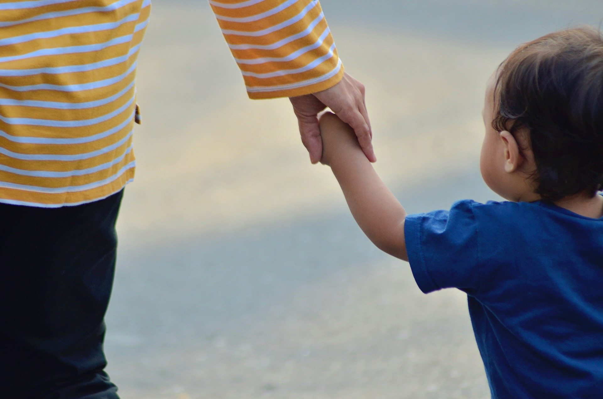 woman holding toddler's hand